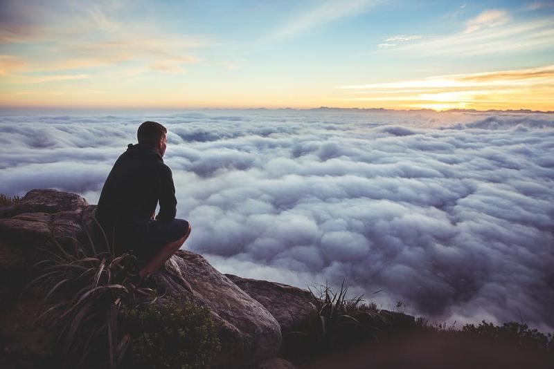 – Decorative: a man sitting alone on top of a mountain, overlooking clouds and a sunrise.